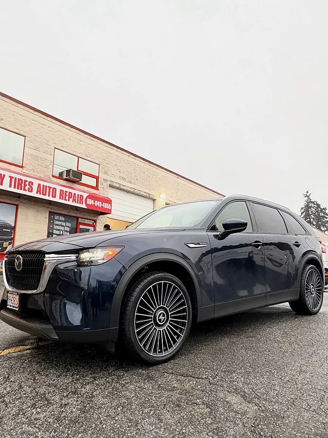 Dark grey crossover on multi-spoke wheels at the shop front