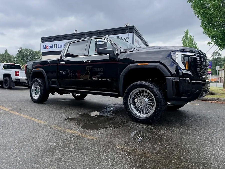 Black GMC pickup on polished wheels in the lot