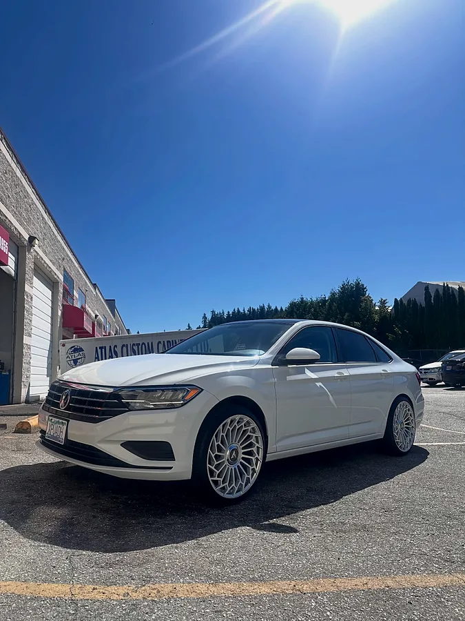 White sedan on machined-face wheels outside the bay